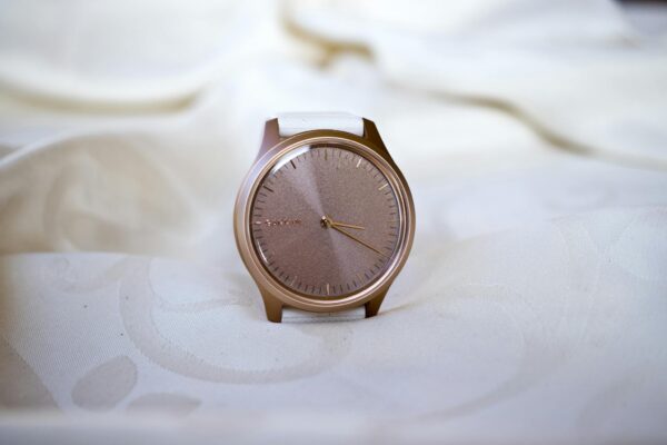 Close-up of a rose gold watch on a white fabric, showcasing minimalistic elegance and style.
